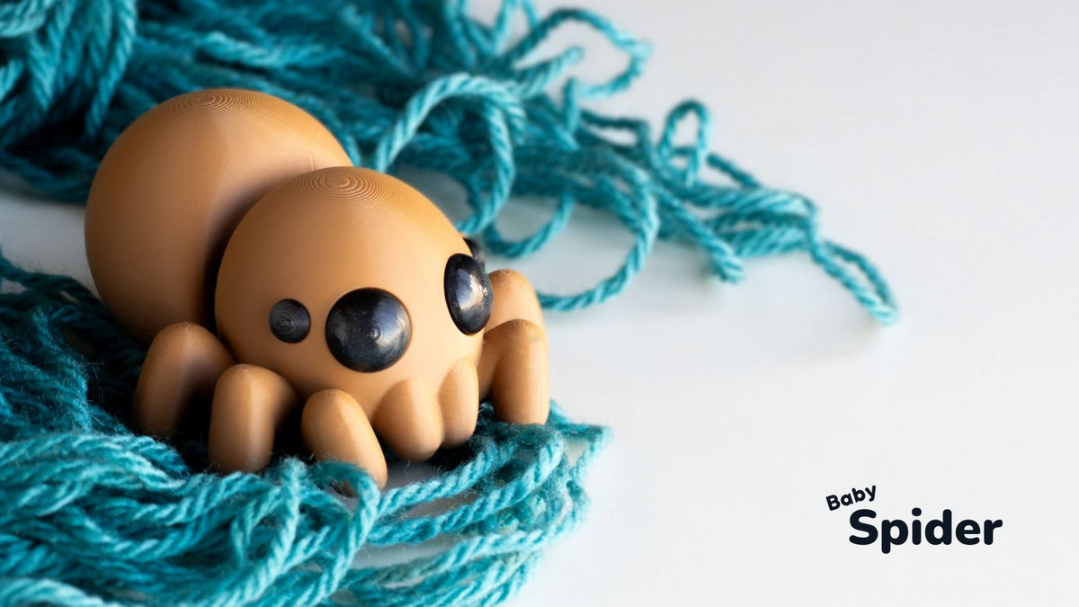 Toy spider on blue yarn with 'Baby Spider' text