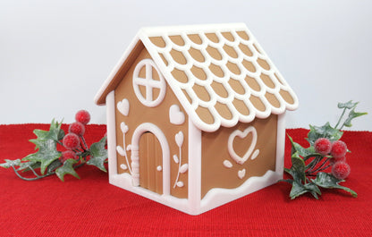 Decorative gingerbread house on a red surface with greenery