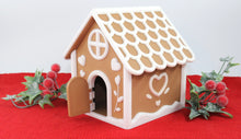 Gingerbread house model on a red surface with decorative elements