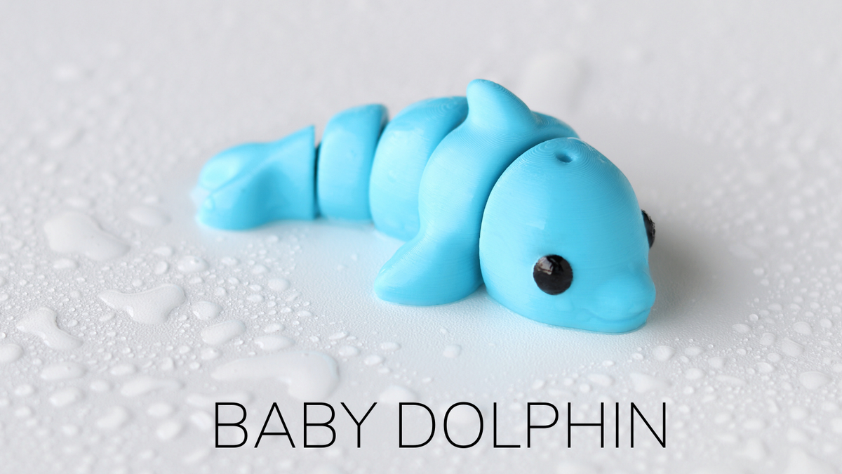 Blue toy dolphin labeled 'Baby Dolphin' on a textured white background