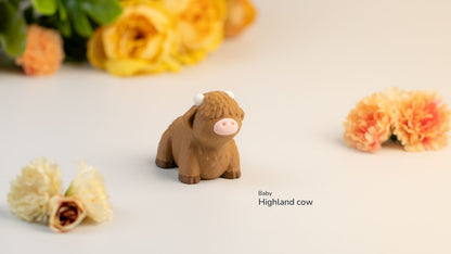 Small brown Highland cow figurine on a light surface with flowers in the background