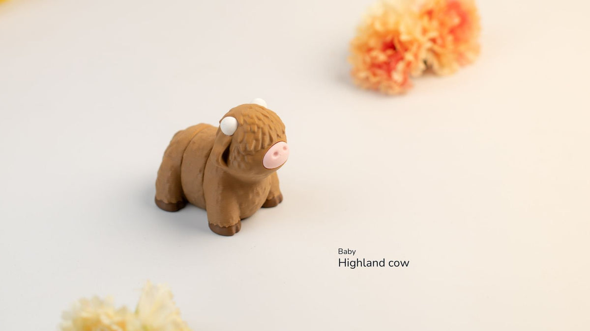 Small brown Highland cow figurine on a light background with decorative flowers.