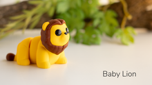 Yellow Baby Lion with a brown mane in front of leaves