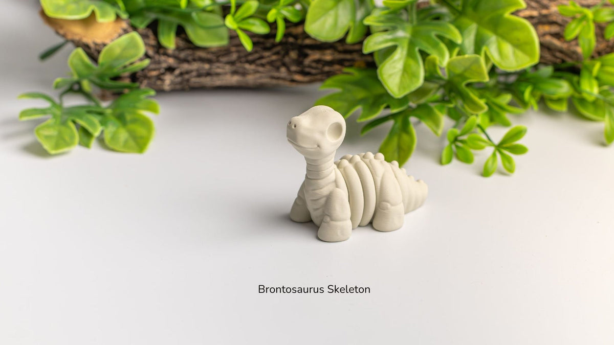 Model of a Brontosaurus skeleton on a white surface with green plants in the background