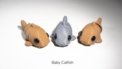 Two Baby Catfish fidget toys in brown and grey
