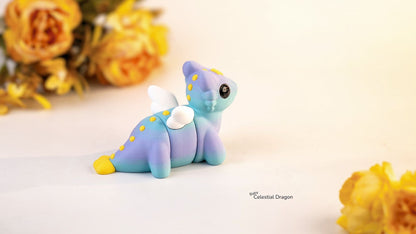 Blue dragon figurine with yellow accents on a light background with yellow flowers