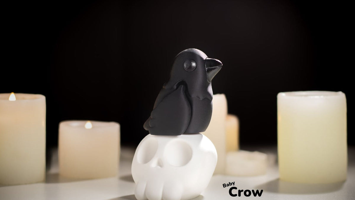 Black crow figurine on a white pedestal with candles in the background