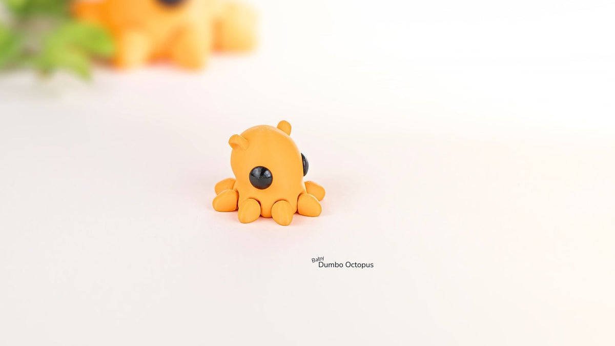 Small orange octopus figurine on a white surface with blurred greenery in the background