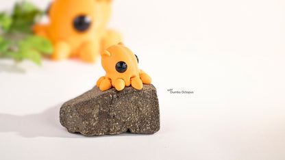 Small orange octopus figurine on a rock with a blurred background