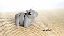 Gray hippo-shaped object on a bamboo mat with 'Baby Hippo' text