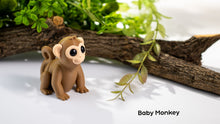 Toy monkey figure on a white surface with greenery