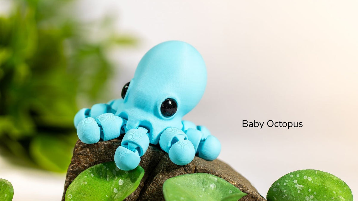 Toy octopus on a rock with green plants, labeled 'Baby Octopus'.