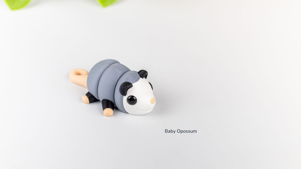 Grey and white Baby Opossum fidget toy on a white surface