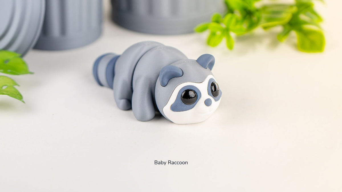 Grey Baby Raccoon fidget toy with leaves behind