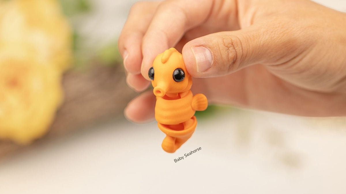 Hand holding an orange Baby Seahorse