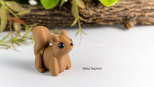 Small brown squirrel figurine on a white surface with greenery in the background