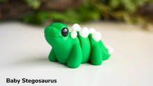 Model of a baby stegosaurus on a white surface with a blurred green background