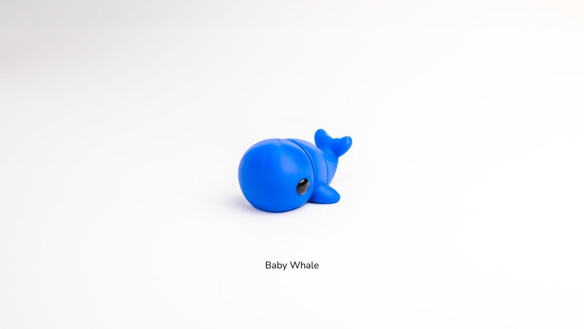 Bright blue Baby Whale fidget toy on a white surface