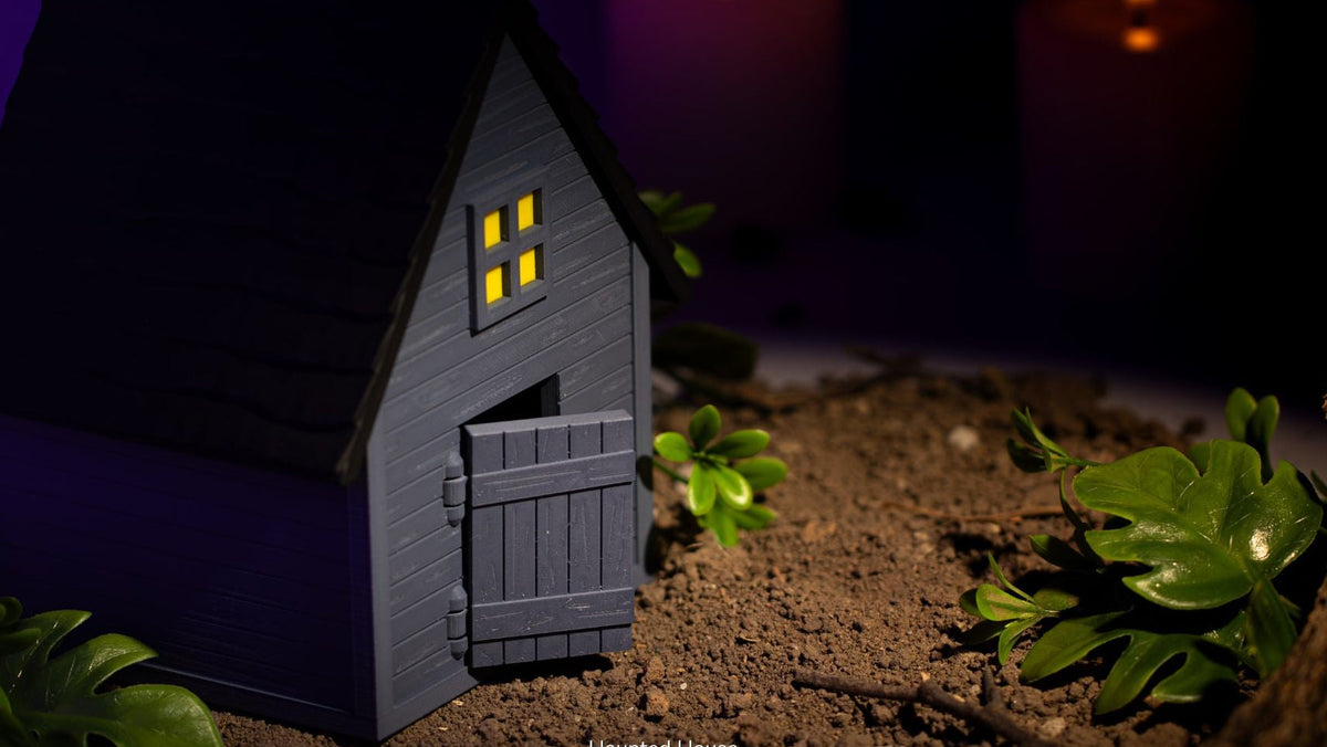 Small model of a haunted house with glowing windows on a dark background