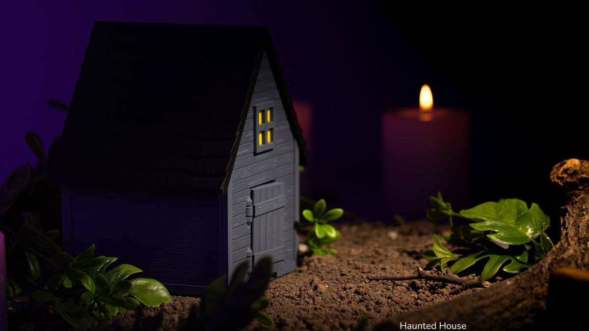 Grey Haunted House with glowing windows and candles on a dark purple background