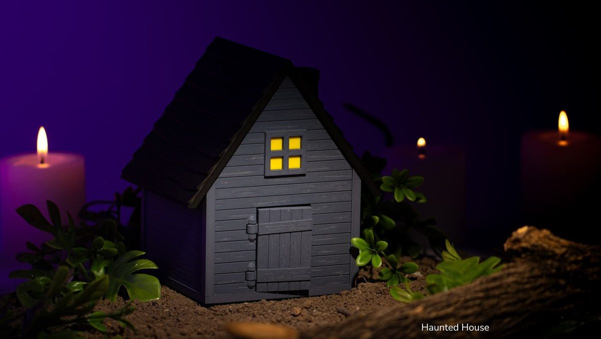 Grey Haunted House with lit windows and purple candles