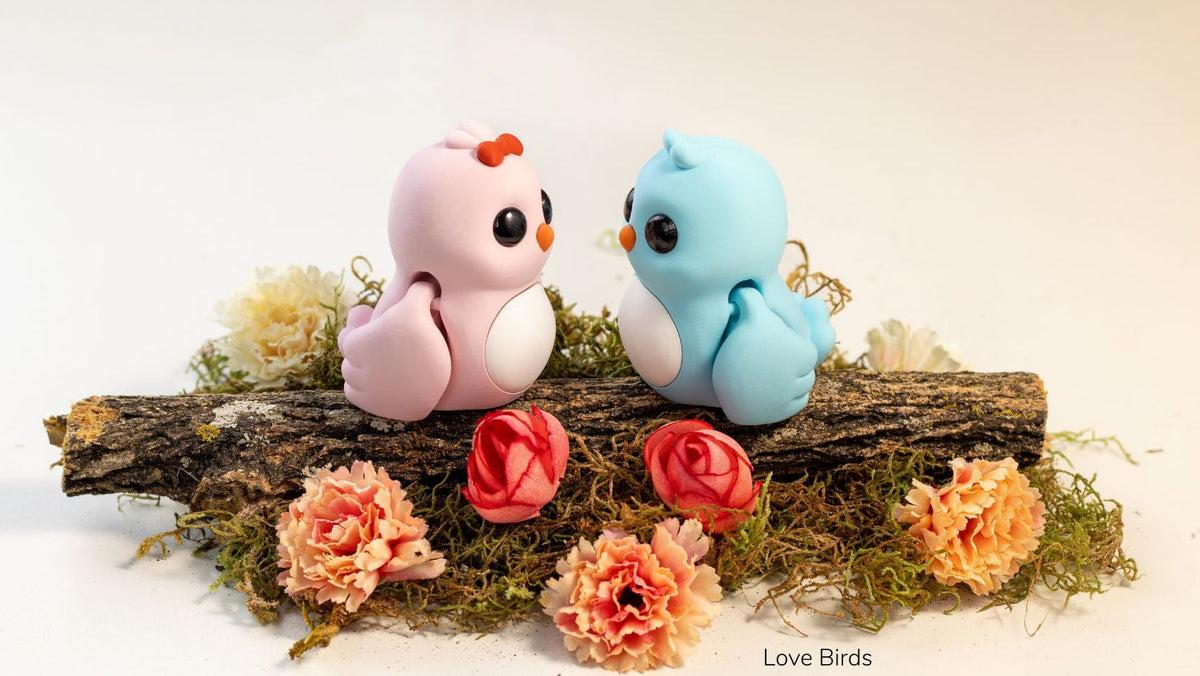 Pink and blue Love Birds sitting on a log with flowers