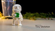 Small skeleton figurine with a green clover, labeled 'Lucky clover Tiny Skeleton', on a blurred background.