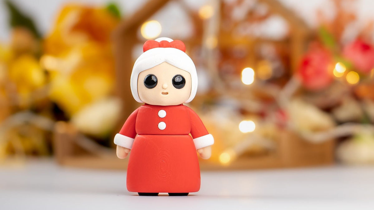 Mrs Claus figure in a red dress and white hat with fairy lights behind