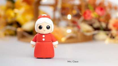 Red and white Mrs Claus figure in front of flowers and lights