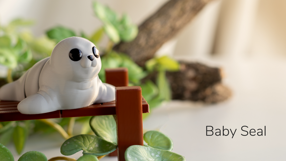 Grey Baby Seal fidget toy on a wooden dock with plants