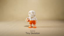 Summer Tiny Skeleton wearing a white hat and orange shorts