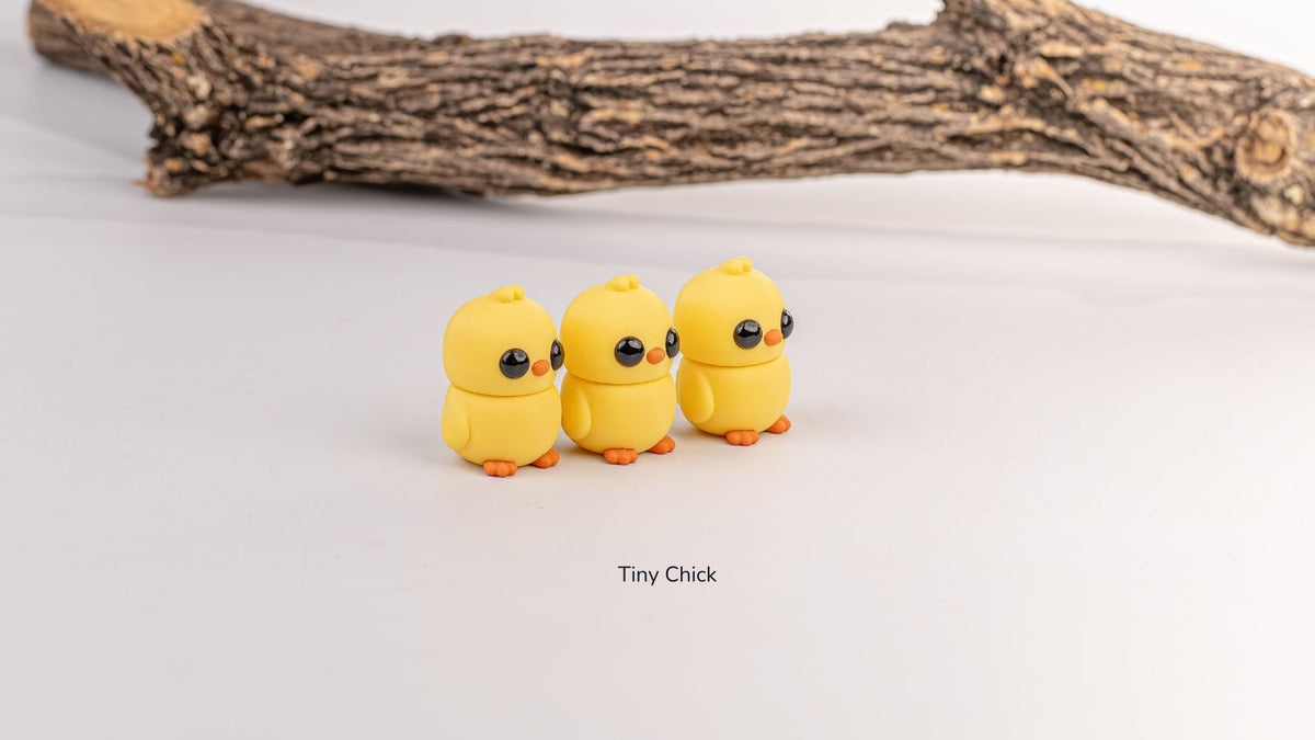 Three yellow Tiny Chicks in a row under a branch