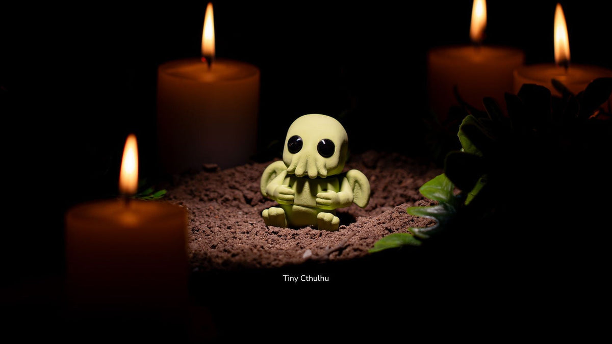 Green Tiny Cthulhu on soil with candles behind