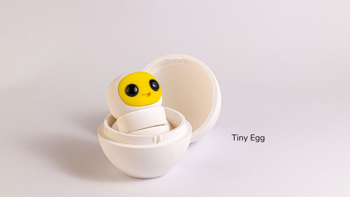 White Tiny Egg character with a yellow chick face in an open shell