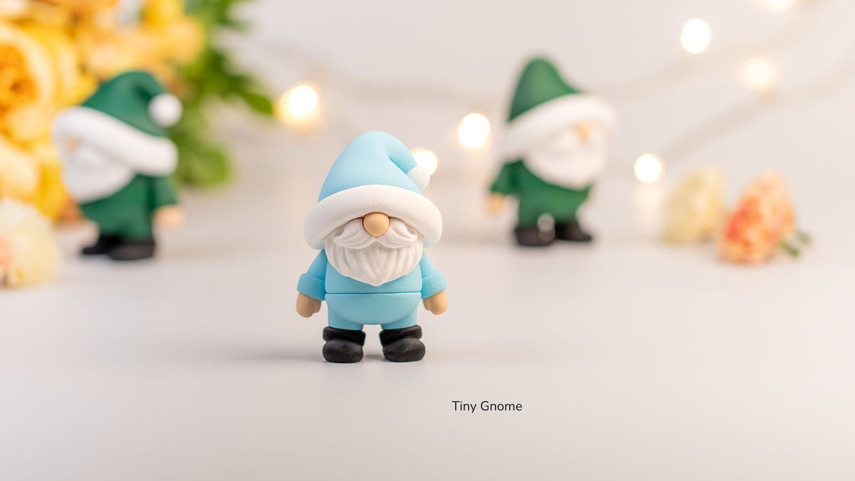 Small gnome figurine with a blue hat and outfit on a light background with blurred decorative elements.