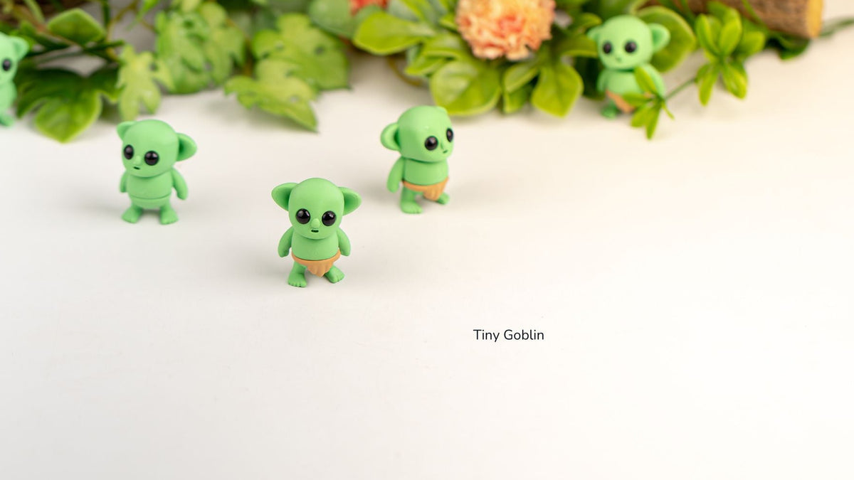 Group of green Tiny Goblin fidget toys under leaves