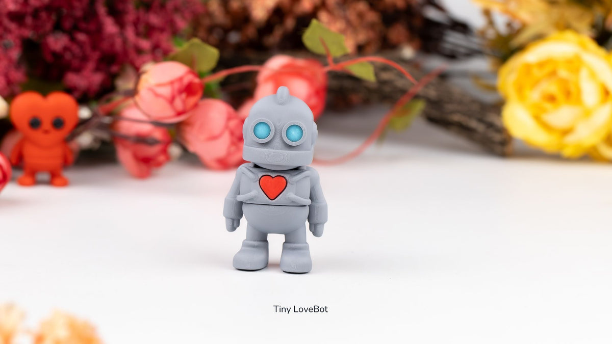 Grey Tiny Lovebot robot with a red heart among red flowers