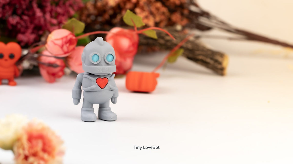 Two grey Tiny Lovebot robots with red hearts among flowers