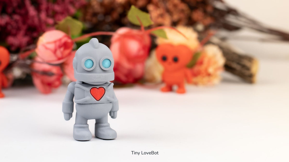 Grey Tiny Lovebot robots holding red hearts beside pink flowers