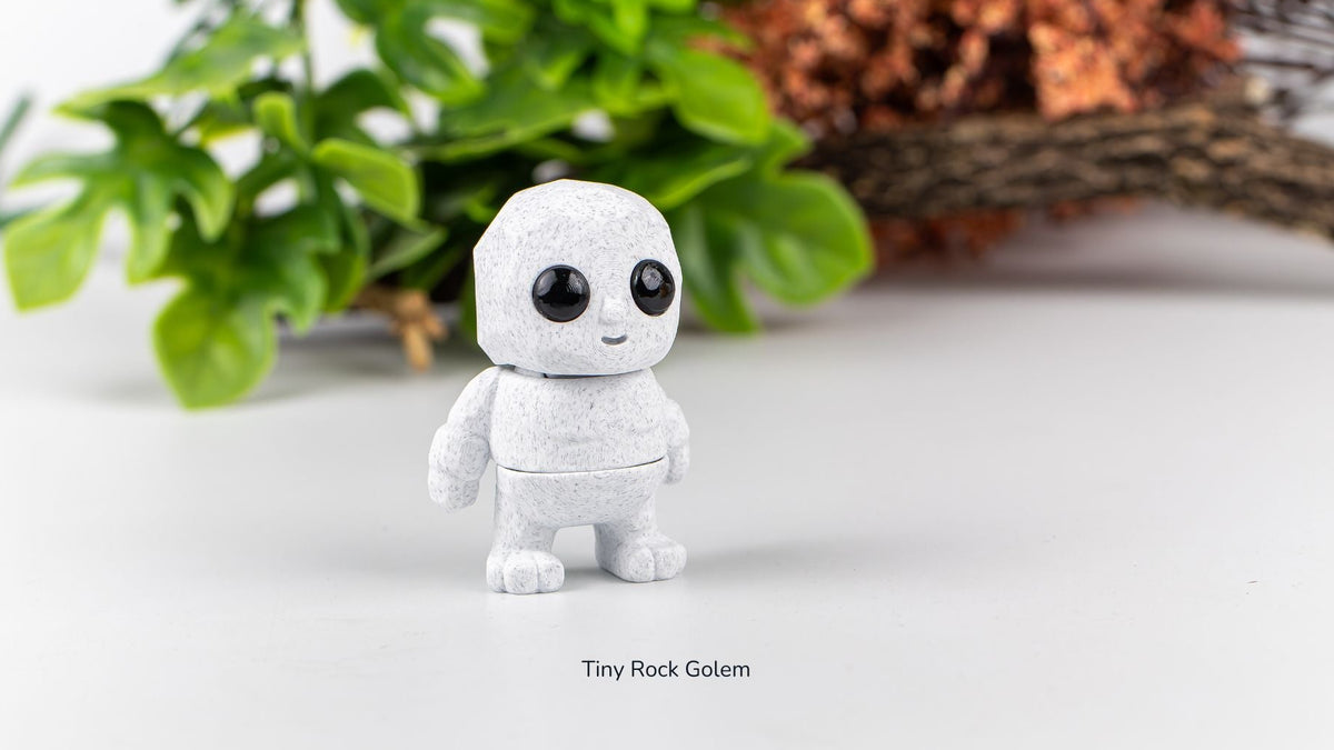 White Tiny Rock Golem fidget toy with plants behind