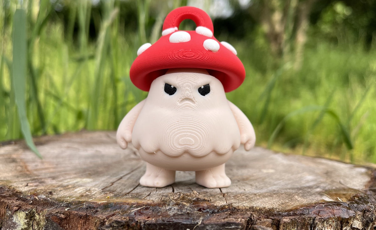 Derek the moody mushroom guard keychain version, with a red loop on top of his spotted mushroom cap